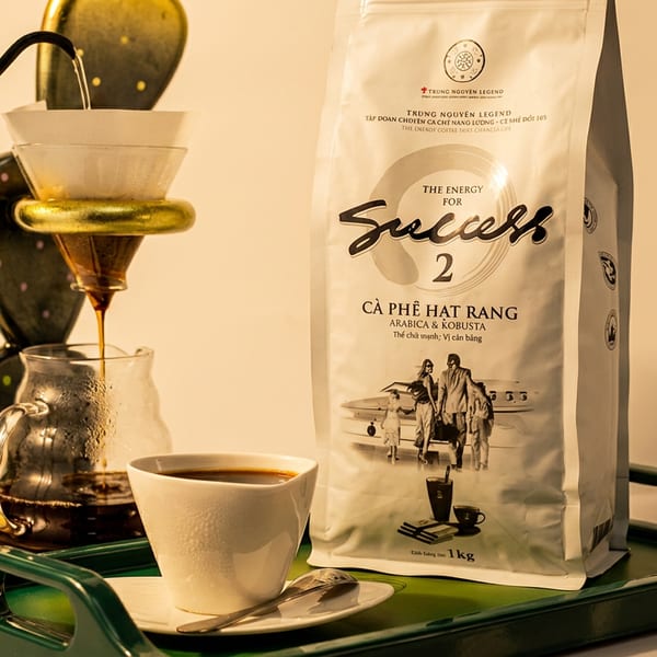 Pour-over coffee setup with a cactus stand, a cup of coffee, and a Trung Nguyen Legend coffee bag on a green tray.